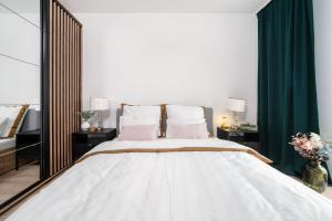 Schlafzimmer mit einem großen weißen Bett und grünen Vorhängen in der Unterkunft Manufaktura Residence - Apartamenty Prestiż z Garażem Podziemnym i Dwoma Łazienkami in Łódź