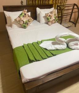 1 cama con sábanas verdes y blancas y 2 toallas en Hotel Gimanhala Thisawewa, en Anuradhapura