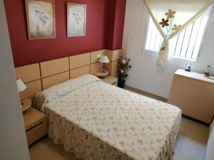 een slaapkamer met een bed, rode muren en een raam bij Vivienda Turística La Marina Azahar in Oropesa del Mar