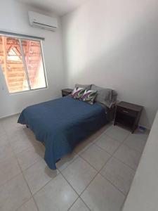 1 dormitorio con 1 cama con manta azul y ventana en Casa Kante, en Puerto Morelos