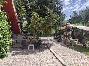 un patio con sillas, mesas y una sombrilla en Casa Rural La Promesa Granada en Víznar