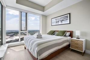 1 dormitorio con 1 cama grande y ventanas grandes en 35th FL w the BEST Views of the Stampede & Saddledome! FREE Banff Pass, Wine, Parking & Gym!, en Calgary