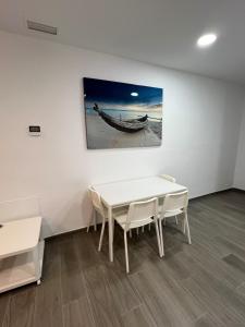 een witte kamer met een tafel en een boot aan de muur bij Apartamentos BEACHYDAYS Metrópolis A in Torremolinos
