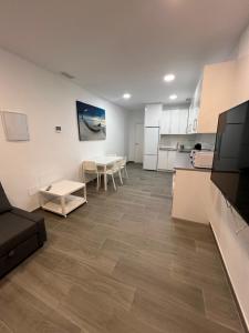 Apartamentos Montalvo Metrópolis A في توريمولينوس: غرفة معيشة مع أريكة وطاولات ومطبخ