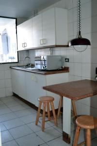 una cocina con armarios blancos, mesa y taburetes en Departamento Amoblado Av. Grecia, en Antofagasta