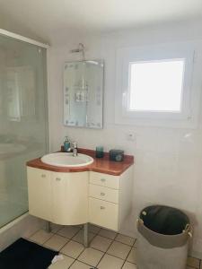 een witte badkamer met een wastafel en een raam bij Le Cocon - Petit déjeuner, Netflix, Jacuzzi* in Carrières-sous-Poissy