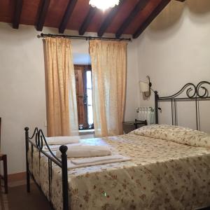 a bedroom with a bed in a room with curtains at Villa Fonte all'Oppio con area piscina recintata in Pienza