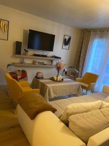 een woonkamer met een bank en een tafel met stoelen bij Le Cocon - Petit déjeuner, Netflix, Jacuzzi* in Carrières-sous-Poissy