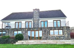 a stone house with a balcony on top of it at Lakeside House in Ballynahinch