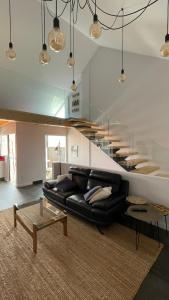 sala de estar con sofá de cuero negro y escaleras en Casa Pieiteiro en Corcubión