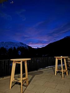 two wooden tables sitting on a balcony with mountains at Berggasthof Grabs in Schruns