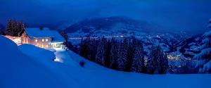 a house on top of a snowy mountain at night at Berggasthof Grabs in Schruns