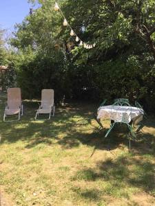 2 sillas y una mesa y una mesa y sillas en un patio en Gîte chez Emy et Seb, en Privas