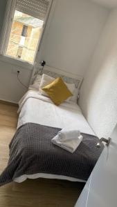 a bed with a yellow pillow and a window at PLAZA ANDALUCIA APARTMENT - Con Encanto in Córdoba
