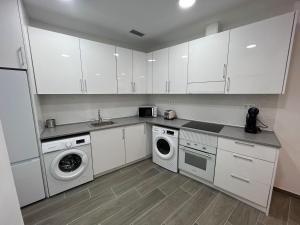 a kitchen with white cabinets and a washer and dryer at Apartamentos BEACHYDAYS Metropolis B in Torremolinos