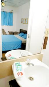 uma casa de banho com um lavatório, um espelho e uma cama em Orison Hostels Managua em Manágua