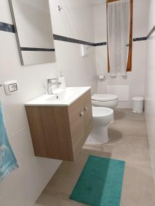 een badkamer met een wastafel, een toilet en een spiegel bij Casa Schiera Solanas in Solanas