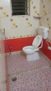 baño con aseo y pared roja en Blue Diamond Service Apartments, en Pune