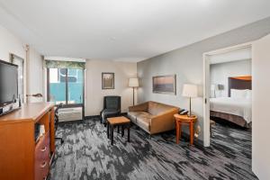 a hotel room with a bed and a couch and a television at Fairfield Inn & Suites Anaheim North Buena Park in Buena Park