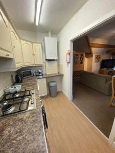 a small kitchen with a stove and a living room at Garnett - Comfy apartment, great location! in Clitheroe