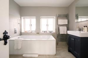 baño con bañera blanca grande y lavamanos en Luxury Boltholes Fallow Grange, en Chichester