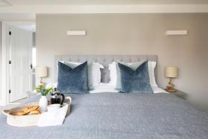 Una cama con almohadas azules y una cesta de pan. en Luxury Boltholes Fallow Grange, en Chichester