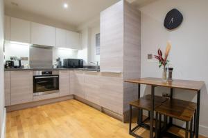 a kitchen with white cabinets and a wooden table at Luxury City Centre Apartment (Weekly Booking) in Hull