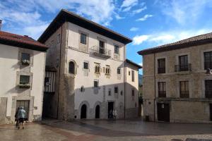 a man standing in front of a white building at Gestiona2R - Apartamento en el casco antiguo Llanisco in Llanes