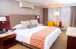 a hotel room with a large bed and a yellow chair at Bogota Plaza Hotel in Bogotá