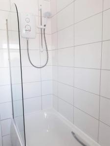 a shower with a white tiled wall at Pulteney Road Apartment in Bath