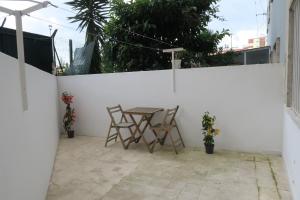a patio with a table and chairs against a white wall at Alvalade CoLiving Hub in Lisbon