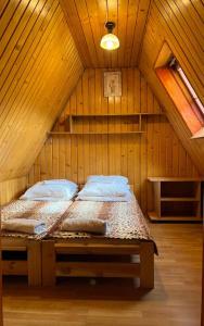 ein Schlafzimmer mit einem Bett im hölzernen Dachgeschoss in der Unterkunft Kwatery u Papieżów in Biały Dunajec