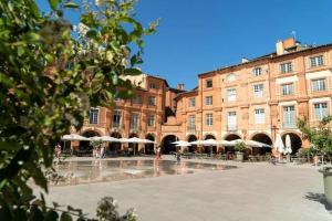 a large courtyard with umbrellas in front of a building at Le Paisiblement Vôtre 3 Ch, Terrasse, Clim, Park in Montauban