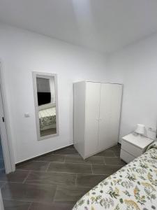 a white bedroom with a bed and a mirror at Apartamentos BEACHYDAYS Metropolis D in Torremolinos