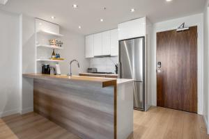 cocina con encimera de madera y nevera en Downtown & Riverside w Walking Trails, FREE Wine, Parking, Gym & Banff Pass!, en Calgary