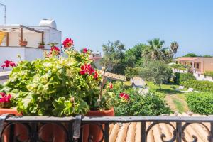 a balcony with red flowers and a garden at Villa d'Eos - Granelli, Pachino in Granelli