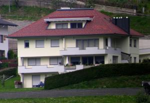 uma casa branca com um telhado vermelho numa colina em Ferienwohnung Reinstadler Ilse em Jerzens