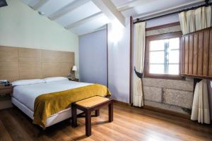 um quarto com uma cama grande e uma janela em Hotel Alda Bonaval em Santiago de Compostela