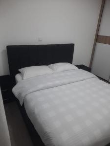 uma cama branca com uma cabeceira preta e almofadas brancas em Goldpark home em Nairobi