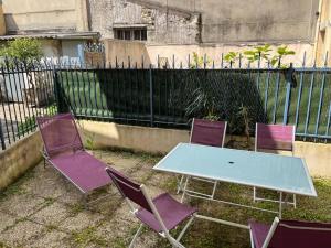 une table et quatre chaises violettes devant une clôture dans l'établissement maison proche du château Versailles, à Versailles
