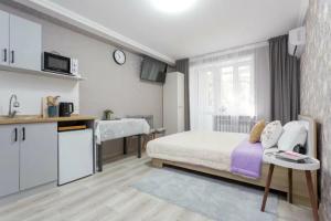 a small bedroom with a bed and a kitchen at Уютная студия в центре in Almaty