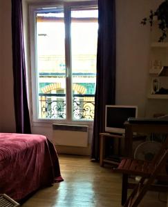 una camera da letto con una grande finestra e un balcone di appartement Paris bohème a Parigi