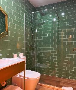 y baño de azulejos verdes con aseo y ducha. en 145 Townhouse, en Ílhavo