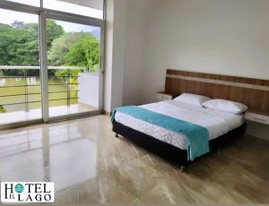een slaapkamer met een bed en een groot raam bij Hotel El Lago in Mocoa