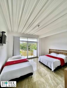 2 Betten in einem Zimmer mit einem großen Fenster in der Unterkunft Hotel El Lago in Mocoa