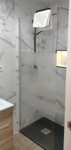 y baño con ducha y paredes de mármol blanco. en Apartamento Centro A, en San Sebastián de los Reyes