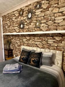 a stone wall behind a bed with pillows on it at "Tranquil Village Hideaway Bungalow"near Kings Lynn in Kings Lynn
