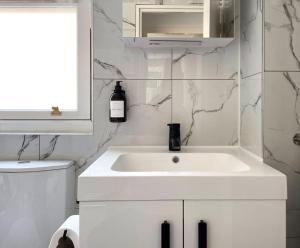 a white bathroom with a white sink and a window at Contemporary central flat in Clerkenwell Green in London