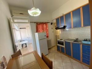 eine Küche mit blauen Schränken und einem weißen Kühlschrank in der Unterkunft Marilena Apartments Anastasiou in Velika