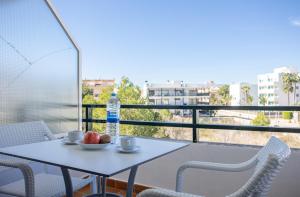 a table with a drink and a bowl of fruit on a balcony at Apartamentos Es Dolç in Colònia de Sant Jordi